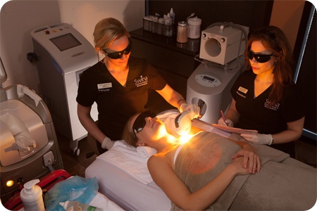 women performing laser treatment women performing laser treatment